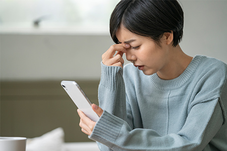 スマホを持ち目を覆う女性画像